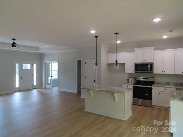 kitchen featuring white cabinetry, appliances with stainless steel finishes, a center island, and hanging light fixtures