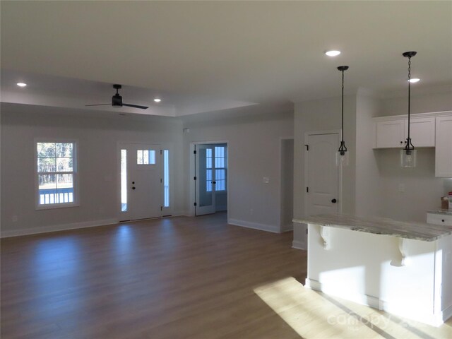 kitchen with wood-type flooring, decorative light fixtures, white cabinetry, and a breakfast bar area