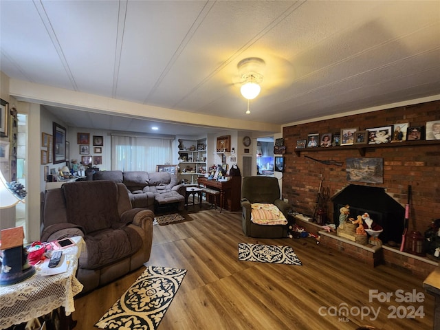 living room featuring hardwood / wood-style flooring, a healthy amount of sunlight, a brick fireplace, and ceiling fan