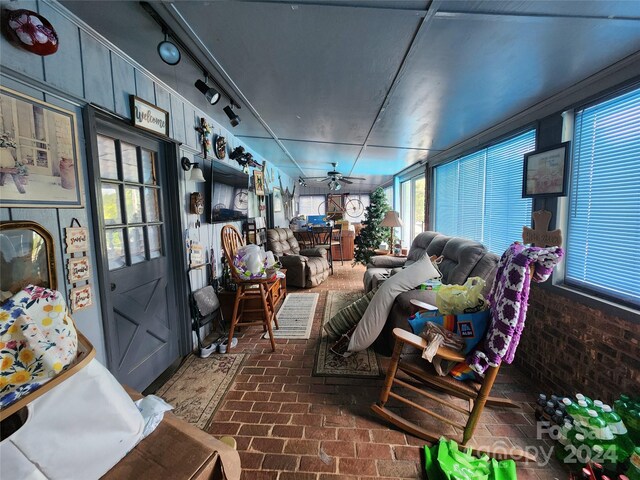 sunroom / solarium featuring rail lighting and ceiling fan