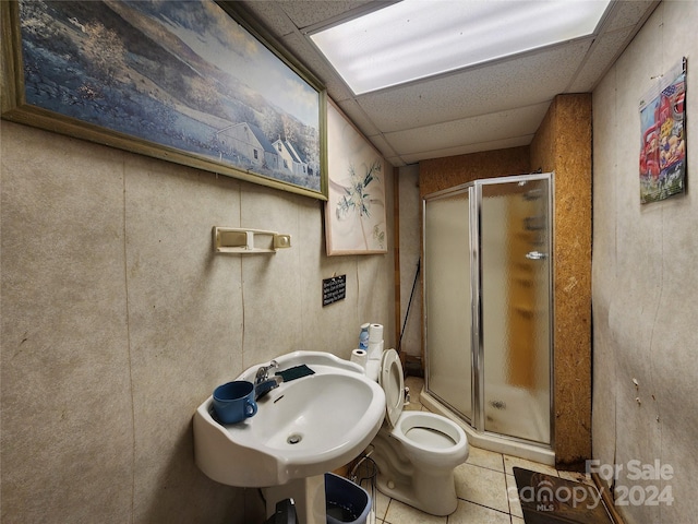 bathroom with a drop ceiling, a shower with shower door, tile floors, and toilet