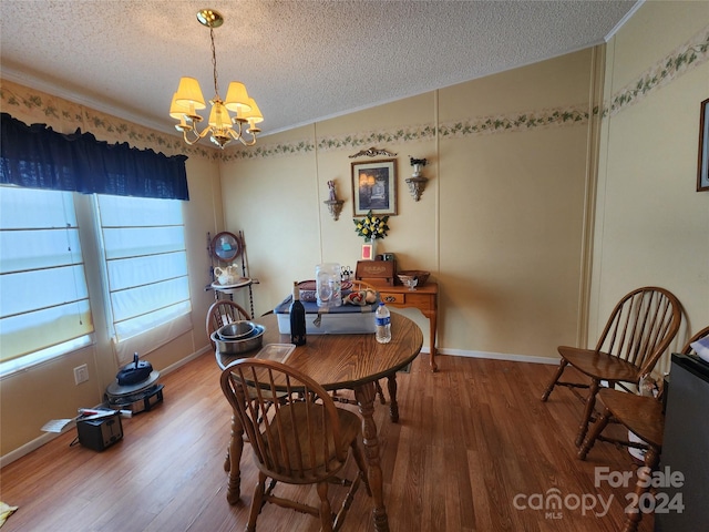 dining area with a textured ceiling, an inviting chandelier, crown molding, and hardwood / wood-style flooring