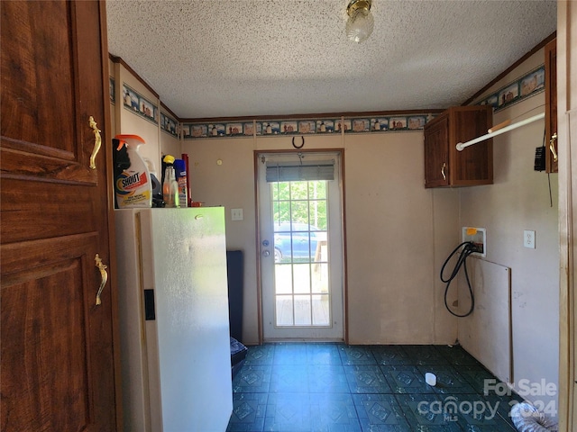 kitchen with a textured ceiling, white refrigerator, and tile flooring