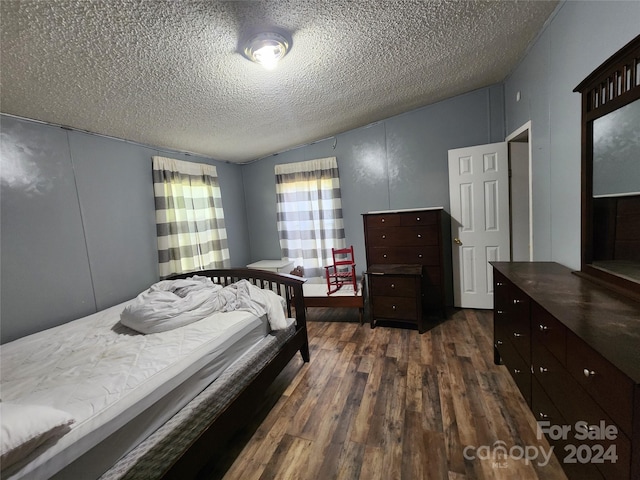 bedroom with dark hardwood / wood-style flooring and a textured ceiling