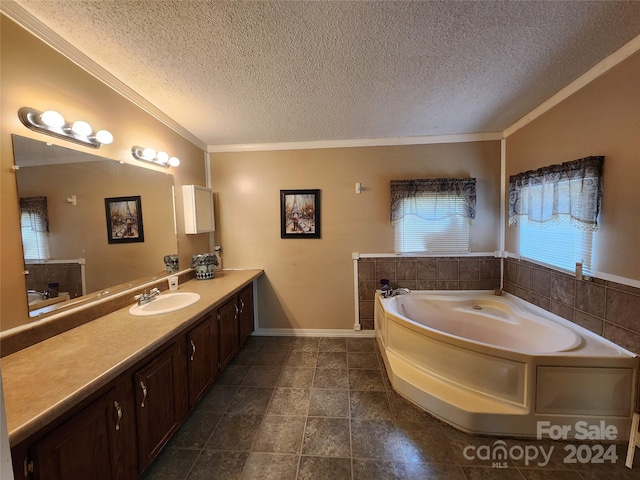 bathroom featuring tile flooring, a textured ceiling, a bathtub, ornamental molding, and vanity