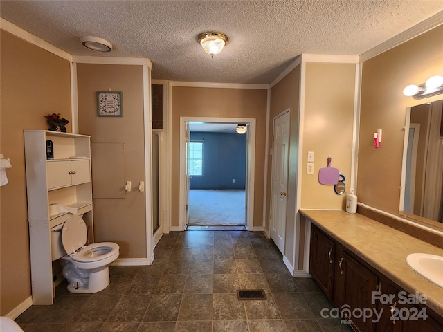 bathroom with vanity with extensive cabinet space, crown molding, tile flooring, toilet, and a textured ceiling