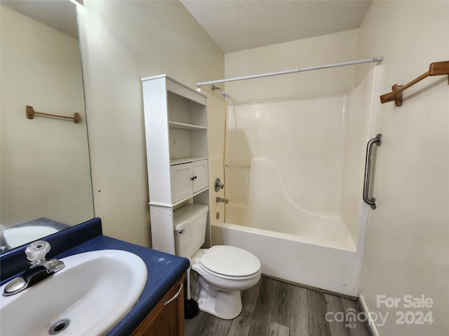 full bathroom with tub / shower combination, a textured ceiling, toilet, vanity, and hardwood / wood-style flooring