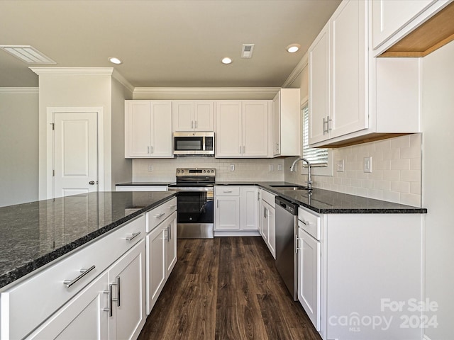 kitchen featuring dark wood-type flooring, stainless steel appliances, dark stone countertops, sink, and white cabinets