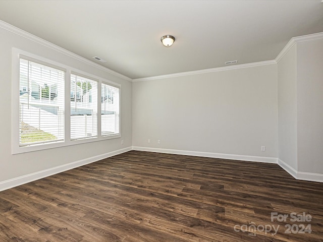 empty room featuring baseboards, visible vents, dark wood finished floors, and ornamental molding