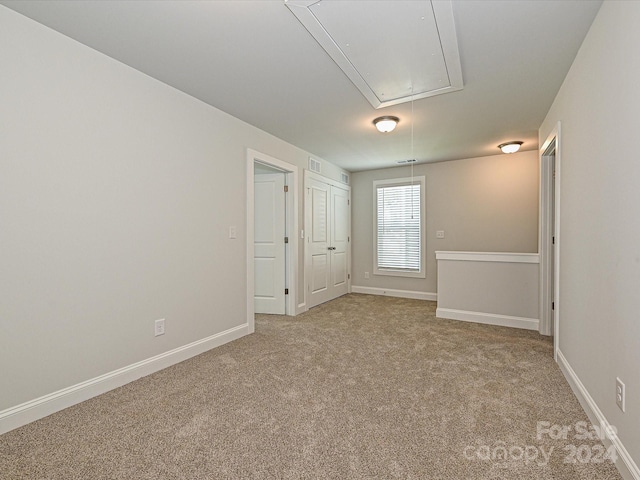 spare room featuring attic access, light colored carpet, visible vents, and baseboards