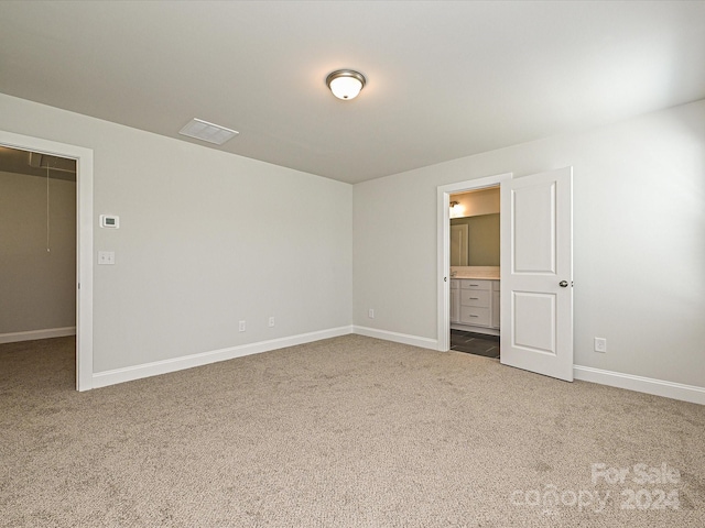 carpeted spare room with attic access and baseboards