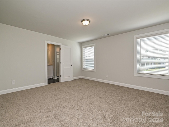 spare room featuring carpet floors, a wealth of natural light, visible vents, and baseboards