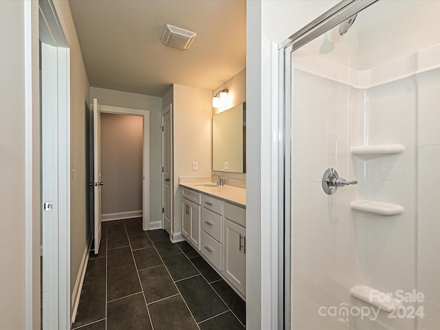 bathroom featuring tile patterned flooring, vanity, visible vents, baseboards, and a shower