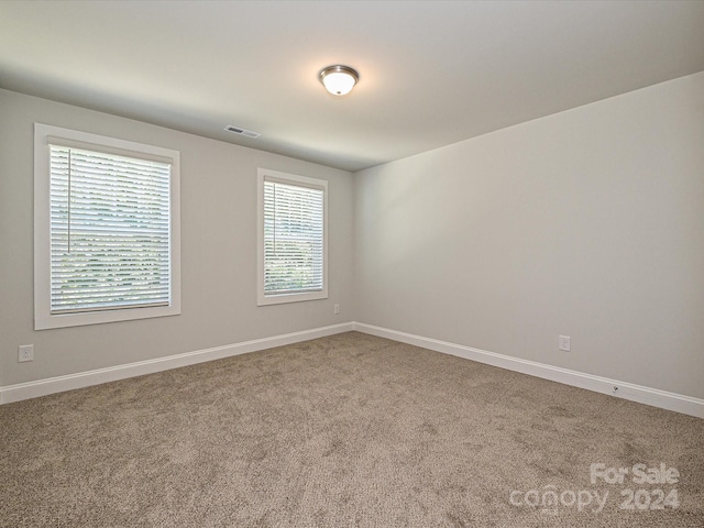 empty room featuring baseboards, visible vents, and carpet flooring