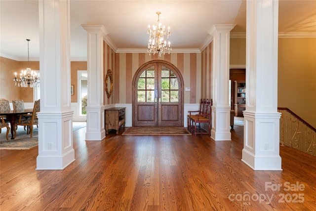 foyer featuring a notable chandelier, dark hardwood / wood-style floors, crown molding, french doors, and decorative columns