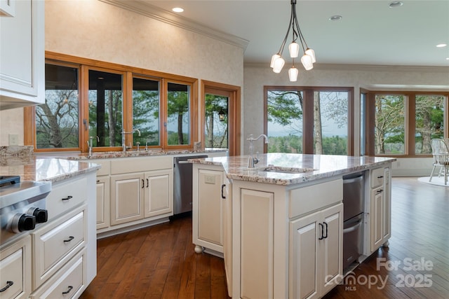 kitchen featuring a center island with sink, sink, crown molding, hanging light fixtures, and light stone counters