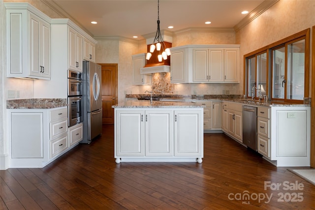 kitchen featuring light stone countertops, pendant lighting, appliances with stainless steel finishes, a center island, and ornamental molding