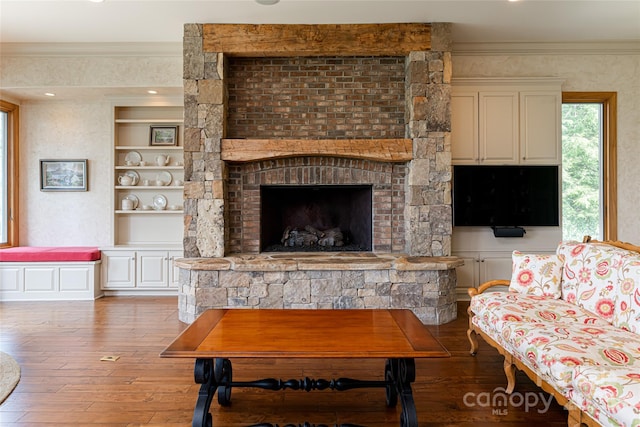 living room featuring wood-type flooring, crown molding, and a fireplace