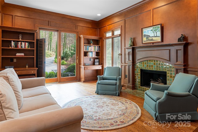 living area featuring ornamental molding, a tiled fireplace, and light wood-type flooring