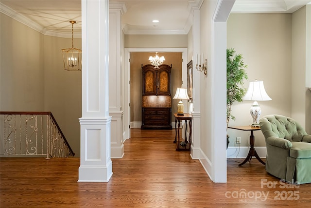 corridor featuring ornate columns, dark hardwood / wood-style floors, ornamental molding, and a notable chandelier