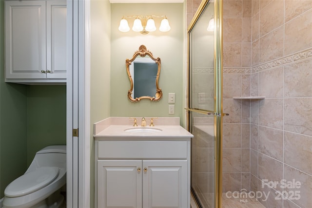 bathroom with toilet, vanity, and a shower with shower door