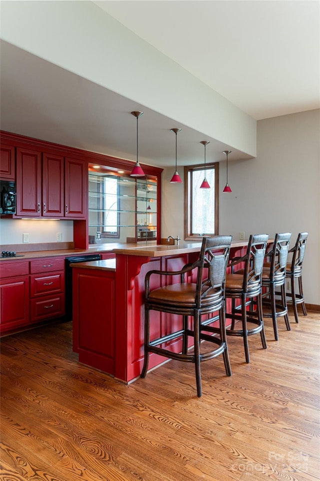 kitchen featuring a kitchen breakfast bar, pendant lighting, hardwood / wood-style floors, and gas cooktop