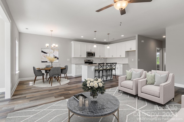 living room with ceiling fan with notable chandelier and hardwood / wood-style floors