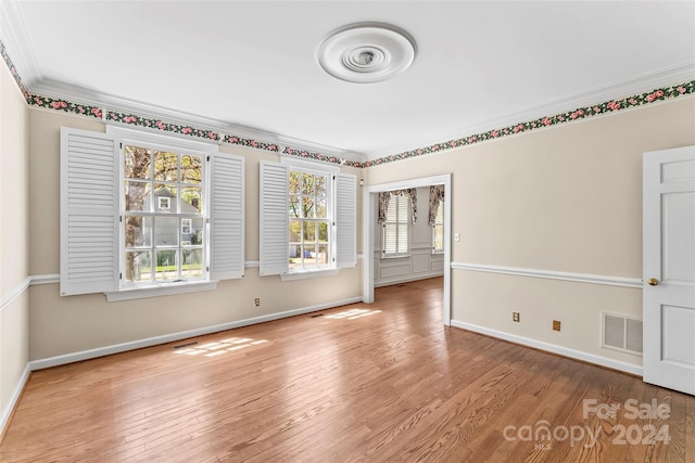 empty room with crown molding and light wood-type flooring