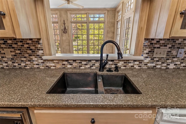 kitchen with dark stone counters, backsplash, ceiling fan, and sink