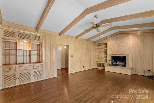 unfurnished living room with built in features, lofted ceiling with beams, dark hardwood / wood-style floors, and a premium fireplace