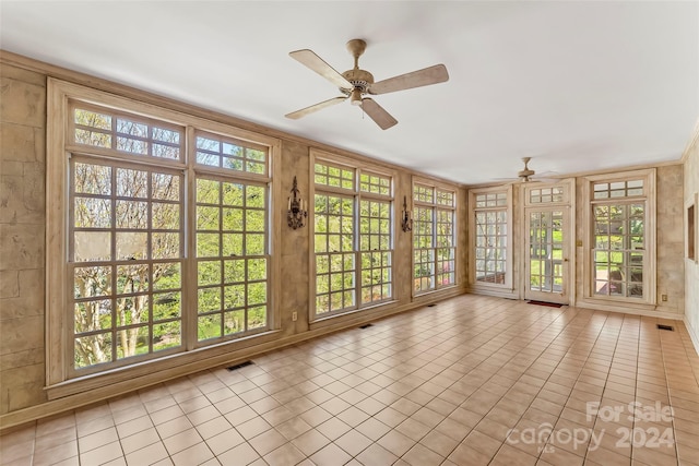 unfurnished sunroom featuring ceiling fan and plenty of natural light