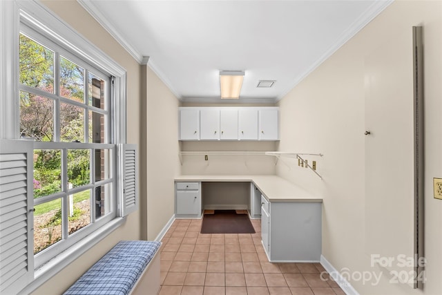 kitchen featuring light tile flooring, white cabinets, built in desk, and a wealth of natural light