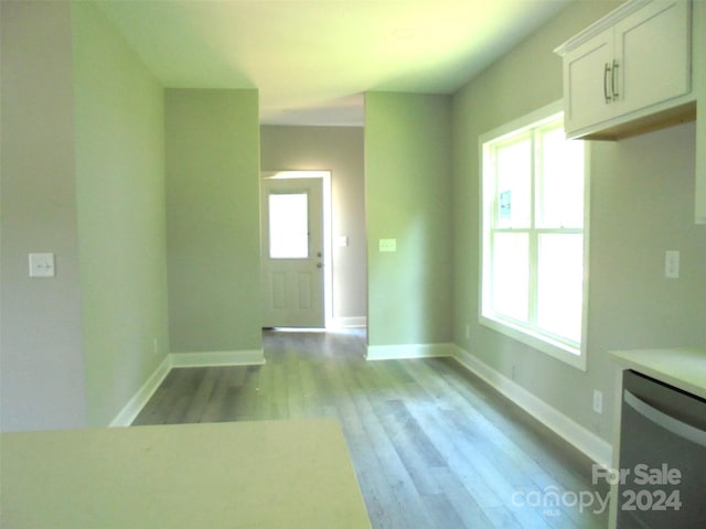 interior space with stainless steel dishwasher, white cabinetry, and light hardwood / wood-style flooring