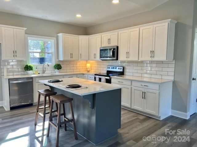 kitchen with appliances with stainless steel finishes, sink, white cabinets, a center island, and a breakfast bar area