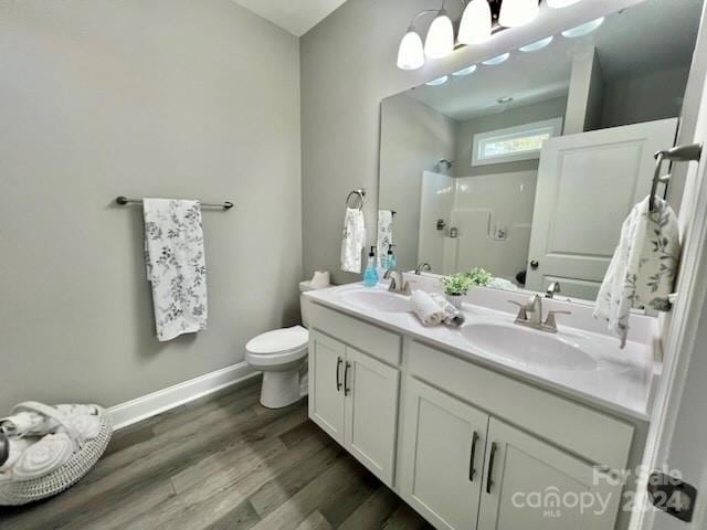 bathroom with toilet, vanity, wood-type flooring, and walk in shower