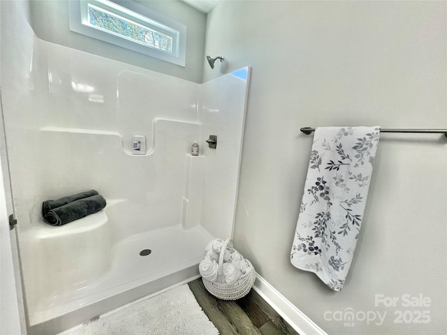 bathroom featuring a shower, baseboards, and wood finished floors