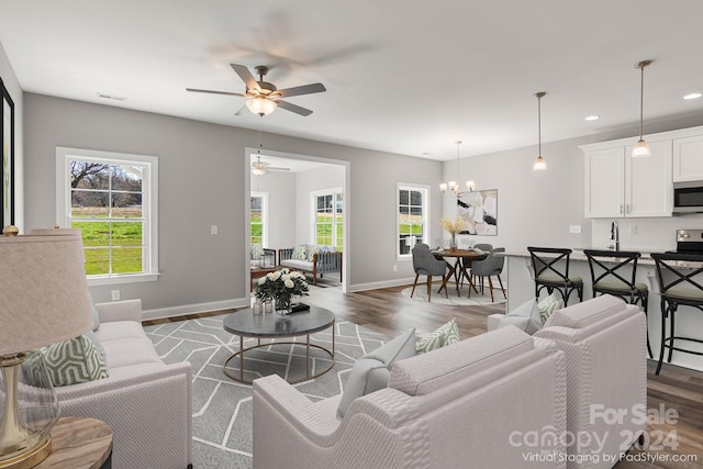 living room featuring sink, plenty of natural light, ceiling fan with notable chandelier, and wood-type flooring