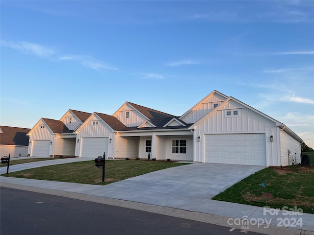 view of front of home featuring a garage, central air condition unit, and a front yard