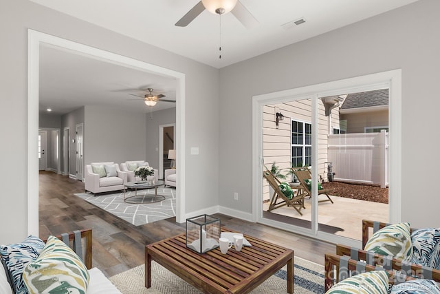 living room featuring ceiling fan and dark wood-type flooring