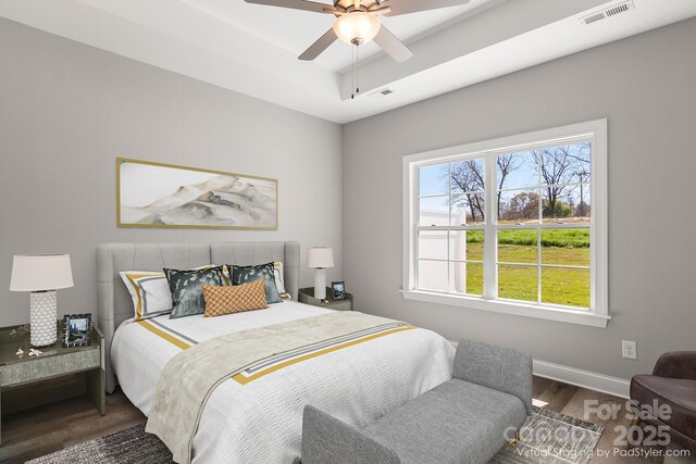 bedroom featuring dark hardwood / wood-style flooring, ceiling fan, and a raised ceiling