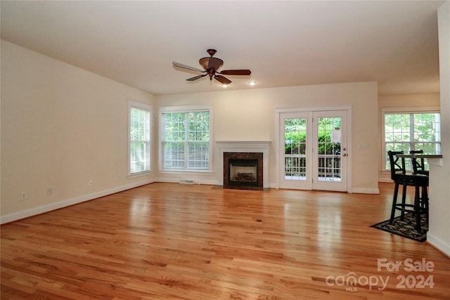 unfurnished living room featuring ceiling fan, a premium fireplace, and light wood-type flooring