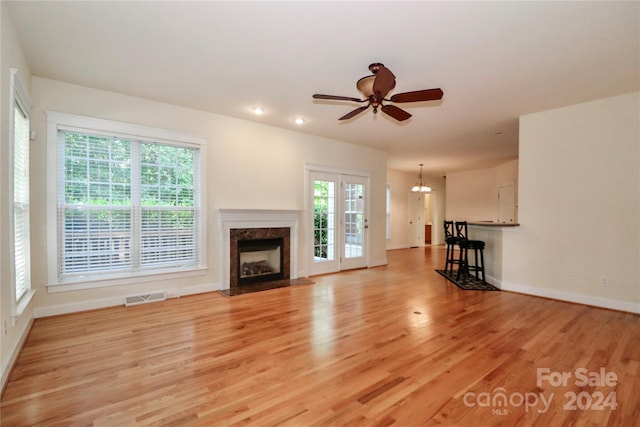 unfurnished living room with a premium fireplace, ceiling fan, and light wood-type flooring