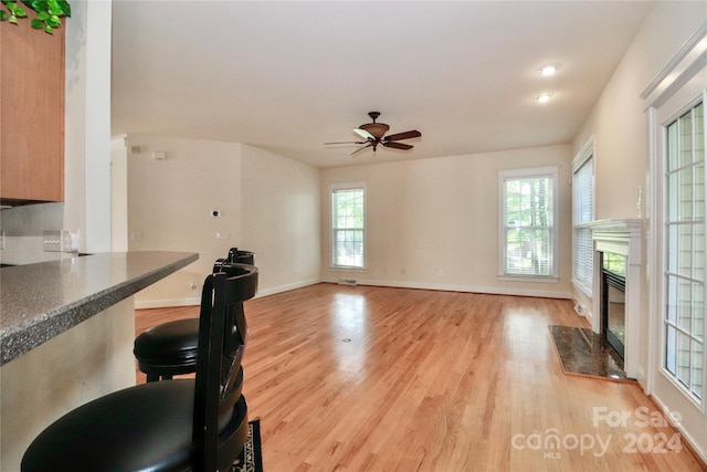 interior space featuring ceiling fan, a fireplace, and light hardwood / wood-style flooring