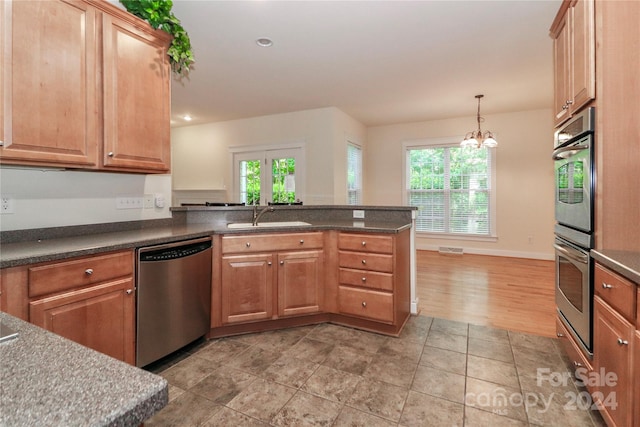 kitchen featuring sink, kitchen peninsula, a notable chandelier, pendant lighting, and stainless steel appliances