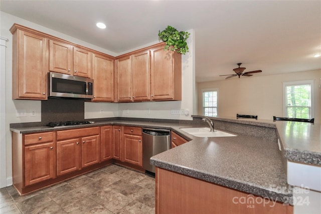 kitchen with ceiling fan, stainless steel appliances, kitchen peninsula, and sink