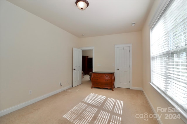 unfurnished bedroom with light colored carpet and multiple windows