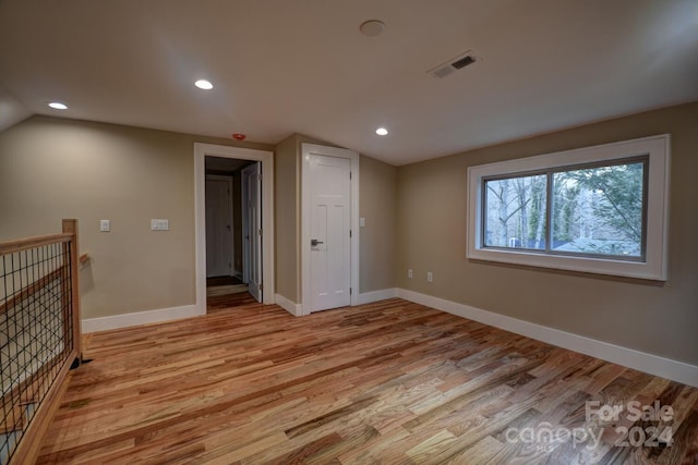 empty room with vaulted ceiling and light hardwood / wood-style floors