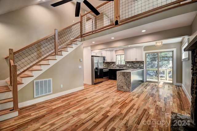 kitchen featuring light wood-type flooring, white cabinetry, stainless steel appliances, tasteful backsplash, and ceiling fan