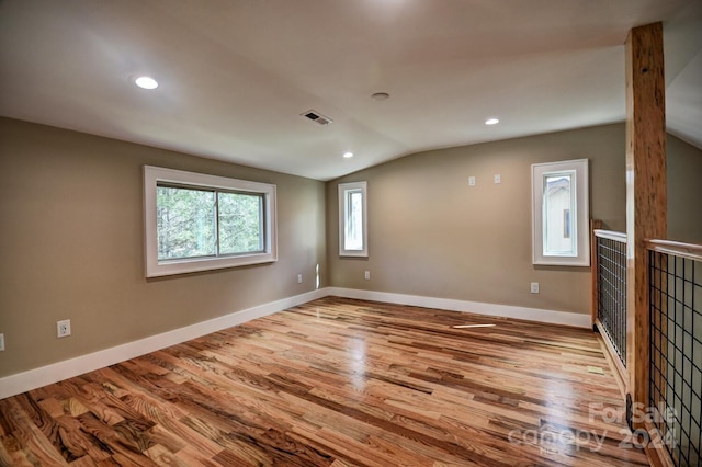 empty room with hardwood / wood-style floors and vaulted ceiling