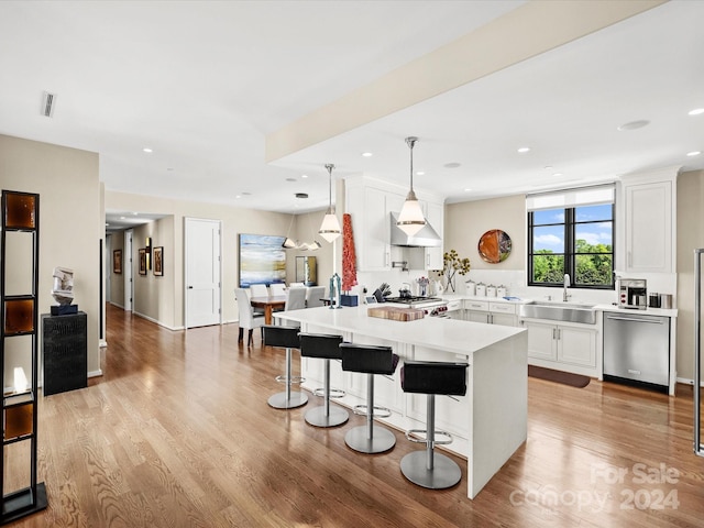 kitchen with light hardwood / wood-style floors, dishwasher, white cabinets, and decorative light fixtures